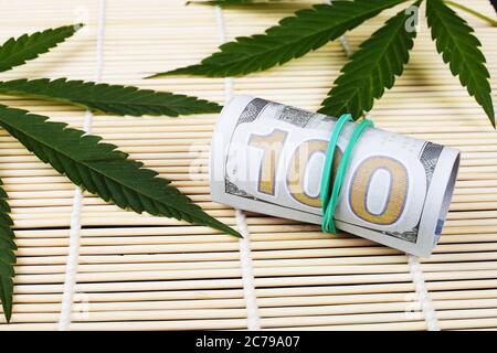 Dollari e foglie di marijuana su un tappeto di bambù Foto Stock