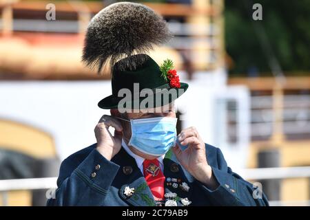 Prien, Germania. 14 luglio 2020. Un locale con costume tradizionale, cappello e barba di camoscio mette su una maschera viso, maschera. | utilizzo in tutto il mondo credito: dpa/Alamy Live News Foto Stock