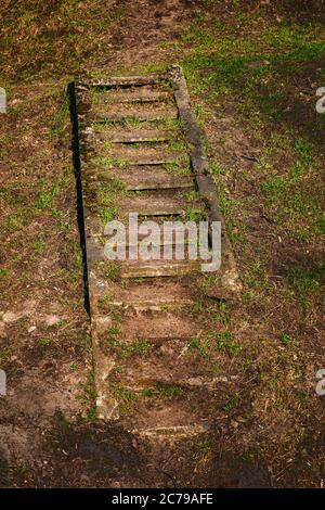 Vecchie scale esterne nascoste in cemento rimangono in collina, appena visibili, sommerse nel terreno Foto Stock