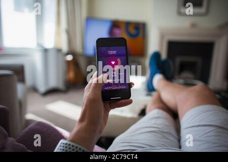 Uomo POV che controlla le statistiche di salute su smartphone in soggiorno Foto Stock