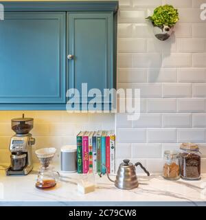 Unità cucina con pareti piastrellate bianche e piano di lavoro in marmo. Macinacaffè e bollitore per infusione Hario sul lato con altoparlante sonos Foto Stock