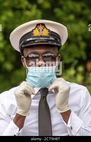 Hampshire, Inghilterra, Regno Unito. 2020. Un ufficiale navale che indossa guanti chirurgici e una maschera facciale durante l'epidemia di Covid-19 nel Regno Unito Foto Stock