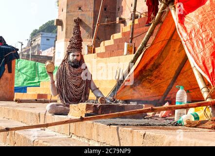 Un Naga Sadhu si siede di fronte alla sua tenda a. I ghat Varanasi Foto Stock