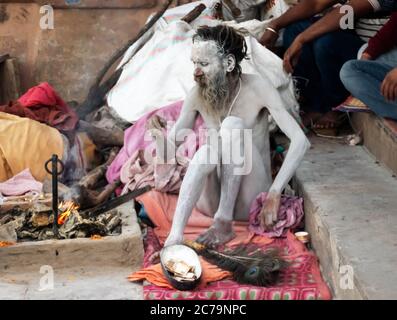 Un Naga Sadhu si siede di fronte alla sua tenda a. I ghat Varanasi Foto Stock