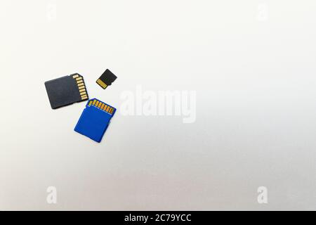 Tre schede SD o schede di memoria per fotocamere e dispositivi digitali e su una superficie metallica grigia, spazio di copia per il testo Foto Stock