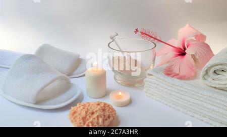 Ambiente Spa e composizione di sfondo Spa con fiore rosa ibisco su sfondo bianco. Banner. Spazio di copia. Asciugamano, candele, fiori, pietre. Massa Foto Stock