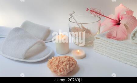 Ambiente Spa e composizione di sfondo Spa con fiore rosa ibisco su sfondo bianco. Banner. Spazio di copia. Asciugamano, candele, fiori, pietre. Massa Foto Stock