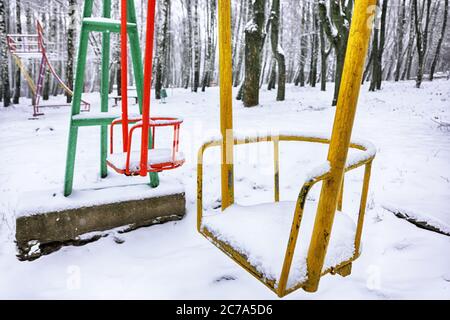 Oscillazione vuota in inverno con neve. I bambini oscillano sotto uno spesso strato di neve Foto Stock