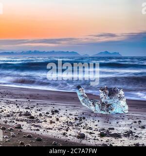 Incredibili pezzi dell'iceberg brillano sulla famosa Diamond Beach alla laguna di Jokulsarlon durante il tramonto. Ubicazione : Laguna di Jokulsarlon, Spiaggia di Diamante, V Foto Stock