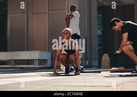 I giovani si divertono mentre si allenano insieme all'aperto. Donne che fanno l'allenamento caldo con gli amici in città. Foto Stock