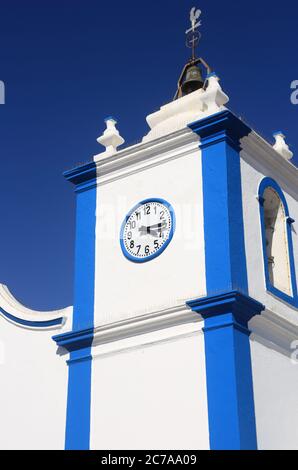 Portogallo, Sines, Vila Nova de Milfontes. La nostra Chiesa della Signora della Grazia. Particolare della facciata bianca e blu e del campanile contro un cielo blu chiaro. Foto Stock
