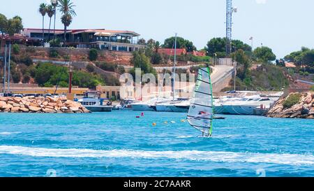 Alicante, Spagna - Luglio, 2020: Windsurf sulla spiaggia di Cabo Roig giorno di vacanza soleggiato. Foto Stock