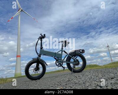 Moderna bicicletta elettrica con turbina eolica sullo sfondo Foto Stock