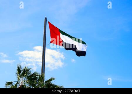 Bandiera degli Emirati Arabi Uniti (Emirati Arabi Uniti) che oscilla nel vento con il cielo blu sullo sfondo Foto Stock