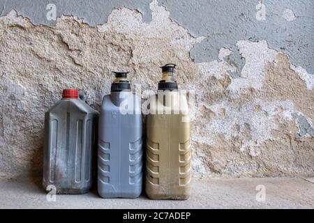 vecchi contenitori dell'olio usati davanti a una parete in un'officina Foto Stock