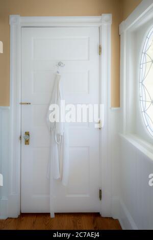 Accappatoio appeso sul retro della porta del bagno con un'atmosfera morbida e soffusa Foto Stock