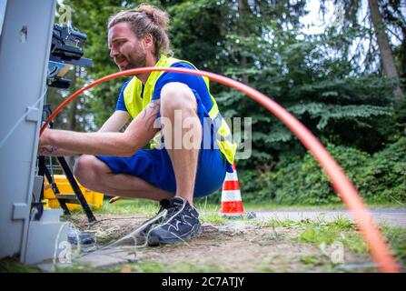 15 luglio 2020, Meclemburgo-Pomerania occidentale, Bentin: Tecnico di fibra ottica Lars Romann prepara un cavo in fibra ottica con sei fibre per le connessioni di casa su un sito di costruzione per l'espansione di Internet a banda larga per la giunzione. La società WEMACOM sta attualmente mettendo a disposizione connessioni in fibra ottica nel distretto di Meclemburgo Nord-Ovest. Finora sono state predisposte circa 5,500 connessioni interne per il collegamento alla rete a fibra ottica veloce. Il Meclemburgo-Pomerania occidentale riceverà circa 850 milioni di euro dal programma federale per l'espansione della banda larga nelle regioni rurali poco servite. Foto: Jens Büt Foto Stock