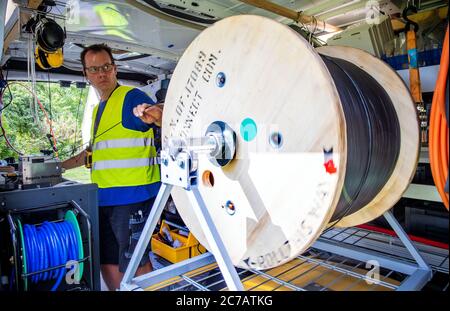 15 luglio 2020, Meclemburgo-Pomerania occidentale, Bentin: In un cantiere per l'espansione di Internet a banda larga, il tecnico della fibra ottica Marc Klöpping soffia un cavo in fibra ottica attraverso un tubo vuoto fino ad una connessione di casa a diverse centinaia di metri di distanza. La società WEMACOM sta attualmente mettendo a disposizione connessioni in fibra ottica nel distretto di Nordwestmecklenburg. Finora sono state predisposte circa 5,500 connessioni interne per il collegamento alla rete a fibra ottica veloce. Il Meclemburgo-Pomerania occidentale riceverà circa 850 milioni di euro dal programma federale per l'espansione della banda larga nella regione rurale non servita Foto Stock