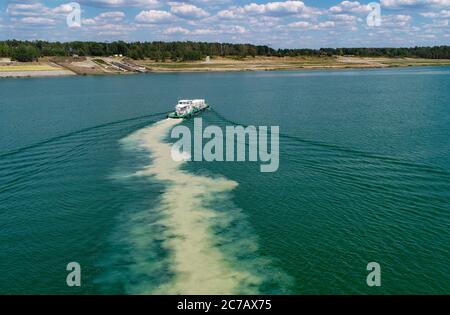 14 luglio 2020, Brandenburg, Sedlitz: Il serbatoio di trattamento delle acque Klara della Lausitzer und Mitteldeutsche Bergbau-Verwaltungsgesellschaft mbH (LMBV) sta diffondendo calce viva nelle acque del lago di Sedlitz per migliorare la qualità dell'acqua (foto aerea con un drone). La miniera a cielo aperto di Sedlitz è stata limata per conto della LMBV da giugno. Questa prima neutralizzazione viene effettuata con il proprio serbatoio di trattamento delle acque della LMBV Klara, già in funzione sul lago Partwitz. La misura dovrebbe essere effettuata entro la fine di settembre. Circa 10,000 tonnellate di cosiddetto quicklim Foto Stock