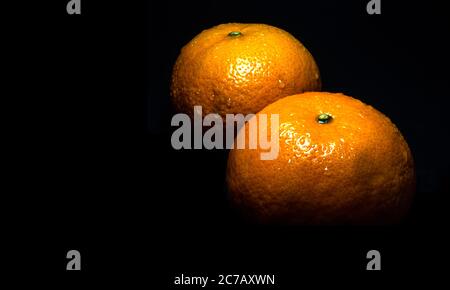 Primo piano della goccia d'acqua su superficie lucida di colore arancione fresco su sfondo nero Foto Stock
