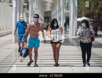 Malaga, Spagna. 15 luglio 2020. Le persone che indossano maschere facciali si vedono camminare lungo la passeggiata della 'Muelle uno' durante il primo giorno di uso obbligatorio di maschere facciali. Nuove infezioni da coronavirus in Spagna dopo l'allentamento delle restrizioni hanno indotto il governo regionale ad imporre l'uso obbligatorio di maschere facciali all'aperto e in luoghi chiusi e spiagge, anche quando osservano una distanza di sicurezza tra le persone. Questa misura cerca di frenare la diffusione della pandemia del coronavirus. Credit: SOPA Images Limited/Alamy Live News Foto Stock