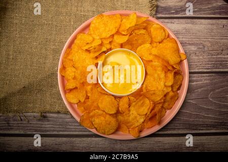 Patatine su un piatto rotondo e una padella con salsa al formaggio. Primo piano Foto Stock