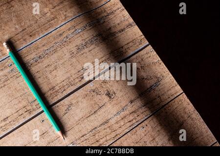 Legno marrone e sfondo nero e matita verde. Sfondo per screensaver e iscrizioni. Foto Stock