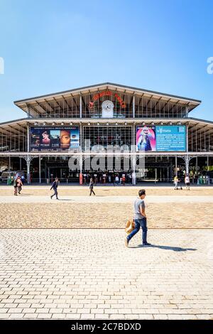 Vista frontale della facciata con orologio e segno della Grande Halle de la Villette a Parigi, un ex macello trasformato in un centro culturale. Foto Stock