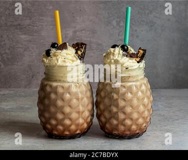 Frullato di cioccolato con gelato, panna montata, bacche, biscotti e waffle, serviti in un vasetto di vetro in muratore. Foto Stock
