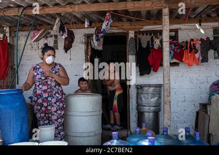 Mexiko Stadt, Messico. 15 luglio 2020. Una famiglia sta in piedi fuori della loro casa. Molte famiglie attualmente soffrono di una carenza di acqua potabile. Il Messico è ora il paese con la quarta morte più registrata per malattia polmonare di Covid-19. Credit: Jacky Muniello/dpa/Alamy Live News Foto Stock