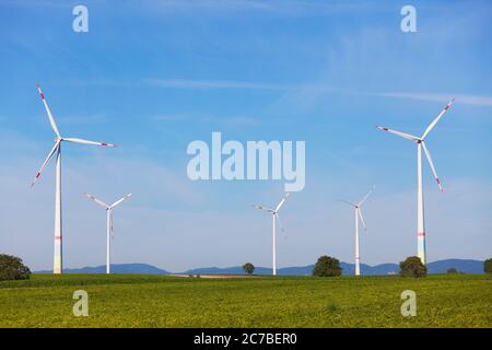 Ruote eoliche rotanti su terreni agricoli contro il cielo blu Foto Stock