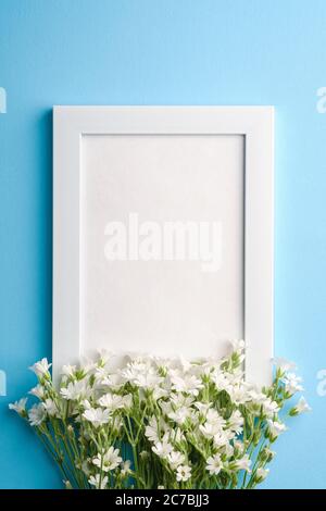 Bianco mockup cornice foto vuota con mouse-orecchio fiori di ceci su sfondo blu, vista dall'alto spazio copia Foto Stock
