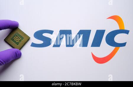 Stone / Regno Unito - 8 luglio 2020: Mettere un guanto mettendo un chip grande del computer accanto al logo SMIC sul documento. Concetto per chip di computer. Foto Stock