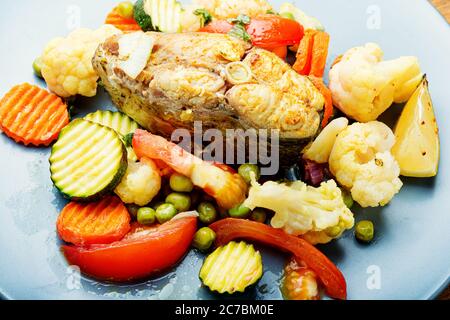 Bistecche di pesce al forno con verdure grigliate sul piatto Foto Stock