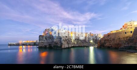 Tramonto sul golfo di Cala Paura con Bastione di Santo Stefano in paese sulle rocce Polignano a Mare, Puglia, Italia, provincia di Bari. Foto Stock