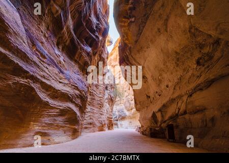 Il Siq, o corridoio, è una formazione geologica di canyon di arenaria che conduce al parco archeologico di Petra, con iconici templi e tombe in pietra scolpita Foto Stock