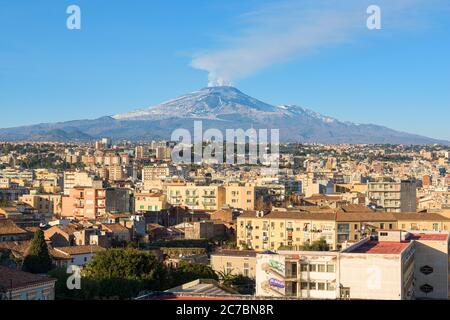 Il vulcano Etna erutta sullo skyline e sui tetti del centro medievale di Catania, Sicilia, Italia Foto Stock