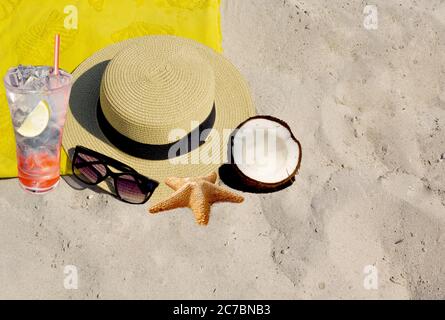 Cappello, occhiali da sole, cocco e stelle marine sulla sabbia Foto Stock