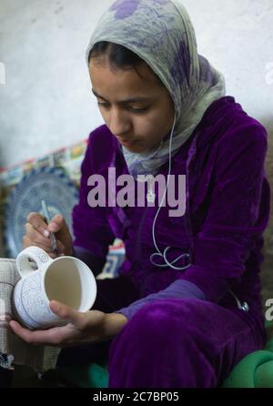 Ragazza marocchina con un velo dipinge una ciotola in una fabbrica di ceramica a Fes, Marocco. Foto Stock