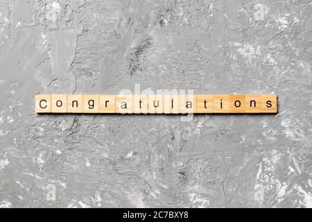 congratulazioni parola scritta su legno blocco. complimenti testo su cemento tavolo per la vostra desing, concetto. Foto Stock