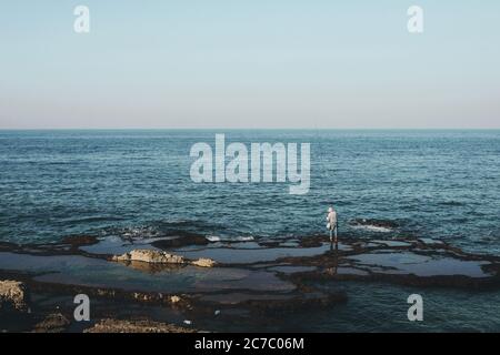Ampio colpo di un pescatore in piedi sulla riva durante giorno Foto Stock