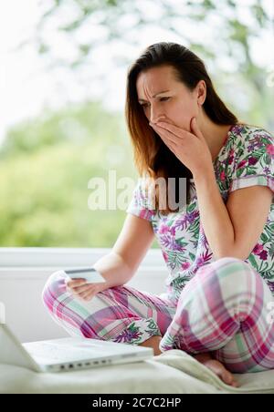 Donna che ha un aspetto sconvolto con il notebook Foto Stock