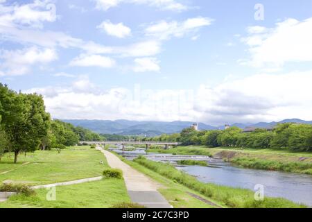 Foto di paesaggio di un fiume a Kyoto durante l'estate con un ponte visibile in distanza Foto Stock