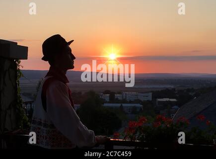Ampio scatto di un uomo moldavo in abiti tradizionali moldavi guardando il tramonto in lontananza Foto Stock