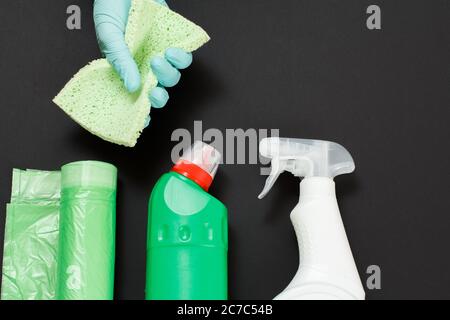 Mano della donna in un guanto in nitrile con una spugna e un set per lavaggio e pulizia su fondo nero. Vista dall'alto. Foto Stock