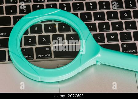 Lente di ingrandimento in vetro sulla tastiera del computer. Una vista dall'alto di un layout piatto. Foto Stock