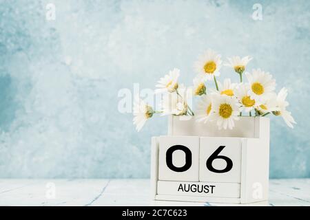 Calendario cubo bianco per agosto decorato con fiori margherita su blu con spazio copia Foto Stock