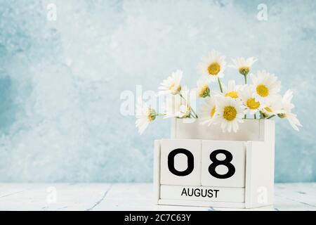 Calendario cubo bianco per agosto decorato con fiori margherita su blu con spazio copia Foto Stock
