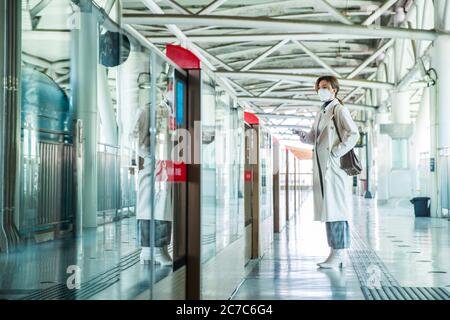 Indossando una maschera della giovane donna si trovava sulla piattaforma della metropolitana Foto Stock