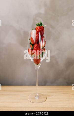 Primo piano di un bicchiere pieno di fragole intere parte anteriore di una parete grigia Foto Stock